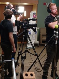 Behind the scenes peek of VPM videographers and actor preparing to do a nasal swab on a nursing home resident with dementia (not seen).