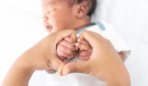 Mother holding child's hands and making her hands into a heart shape