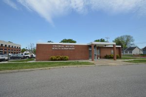 A one story brick building with green grass and trees behind it.