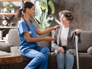 A nurse helps a lady with a cane.