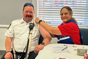 A person vaccinates a person in uniform.