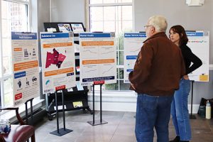 Two people discuss five posters in a lobby.