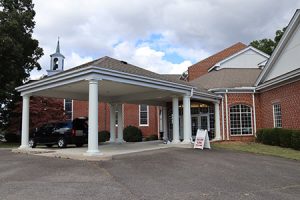 A brick church with a white column carport.