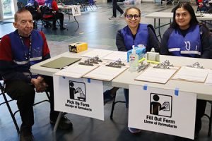 Three people sit behind a registration table.