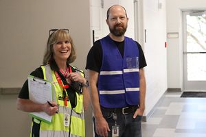 Two people wearing vests smile at the camera.